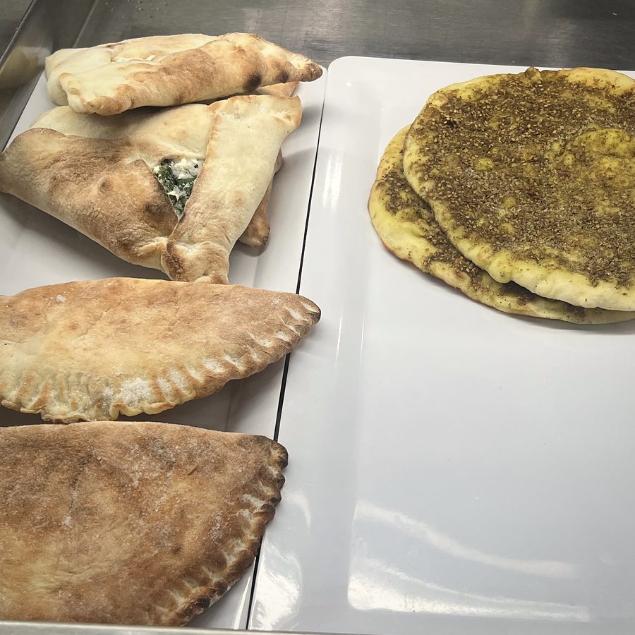 Baked pies and a za'atar flatbread on white display trays
